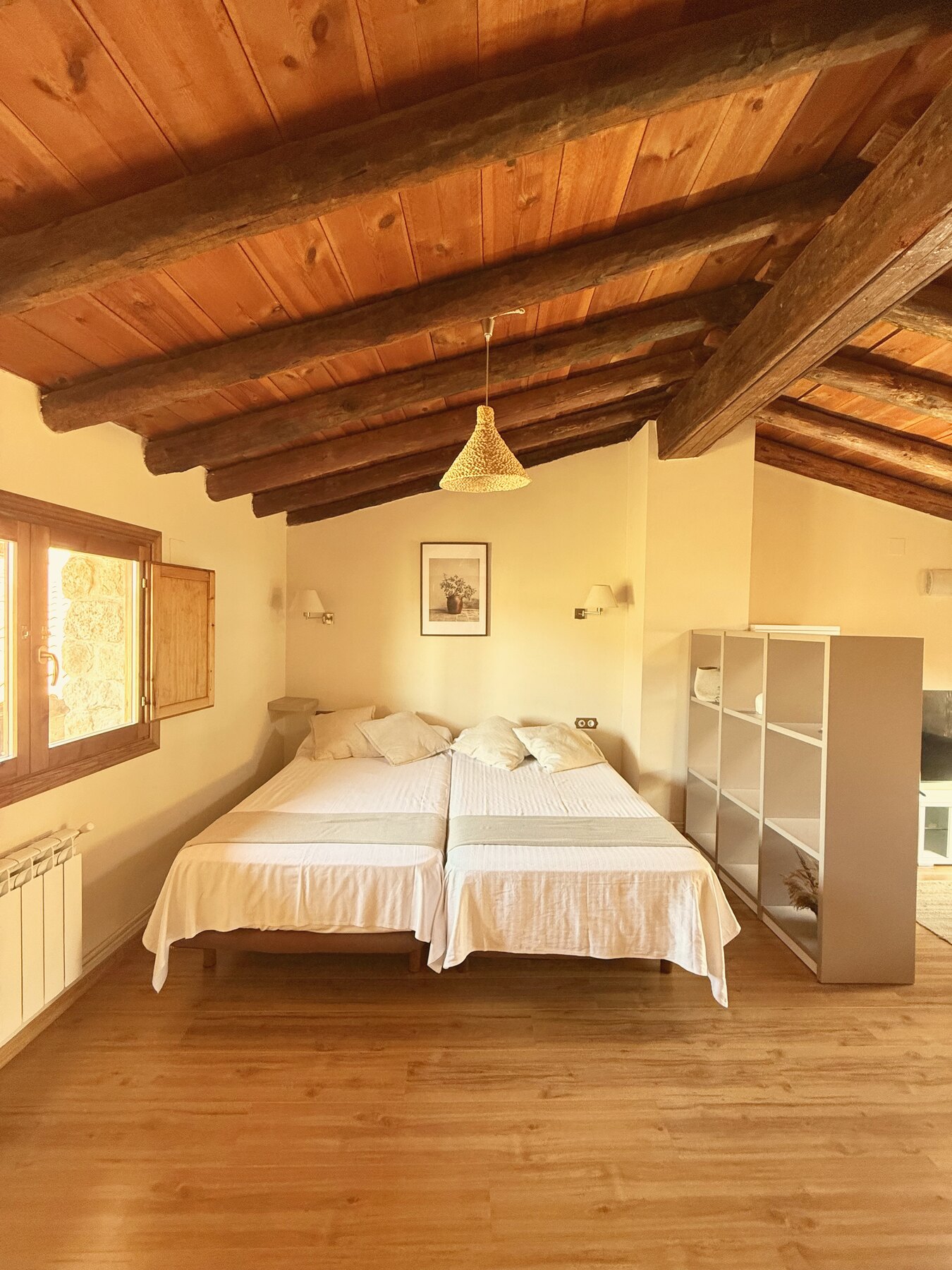 Dormitorio del ático con cama extragrande bajo vigas de madera